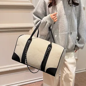 Large contrast canvas tote bag with black trim and chain detail for travel and commute