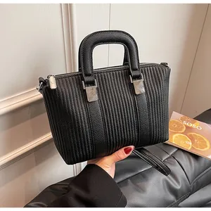 Detail of black tote bag with vertical pleat texture and silver metal zipper hardware