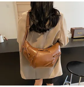Sac à bandoulière marron en forme de croissant avec nœuds décoratifs porté par une femme