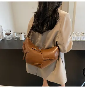 Vue latérale d'un sac à bandoulière marron en demi-lune avec des nœuds sur un mannequin