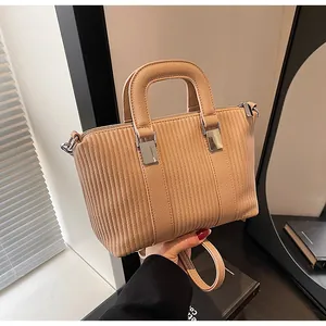 Detailed close-up of light brown tote bag with vertical embossed texture and silver hardware