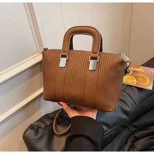 Detail of brown tote bag featuring vertical texture, silver hardware and round handles