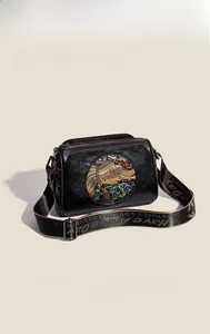 Close-up of vintage crossbody bag with elephant embossed pattern and jacquard strap