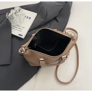 Detail view of khaki pleated tote bag with silver zipper closure and dark inner lining