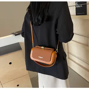 Vue arrière d'un mannequin portant un sac bandoulière en cuir marron et toile avec boucle
