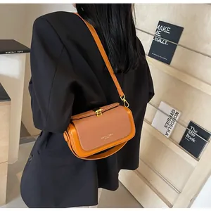 Détail du sac bandoulière orange avec tissu texturé, similicuir et boucle dorée chic