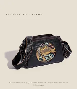 Detailed view of the embossed gold elephant and floral motif on black leather pillow bag