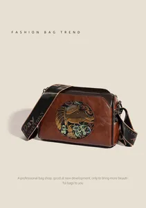 Detail of vintage brown leather bag with ethnic elephant embossing and wide shoulder strap
