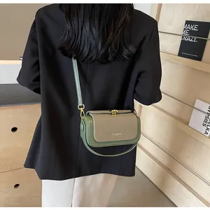 Détail d'un sac bandoulière en cuir vert avocat et tissu beige avec boucle dorée