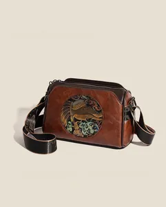 Detailed view of vintage brown leather bag with colorful elephant relief and wide strap