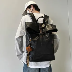 Waterproof black roll-top backpack with brown buckle and bear charm for commute