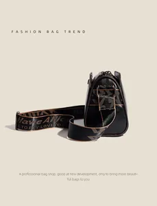 Detail view of black leather pillow bag featuring floral embossing and wide jacquard strap