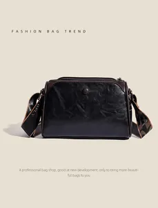 Close-up of vintage embossed leather handbag with wide woven strap and metal zipper