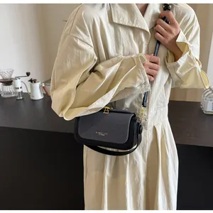 Détail du sac bandoulière avec rabat en tissu gris et cuir noir porté par un mannequin