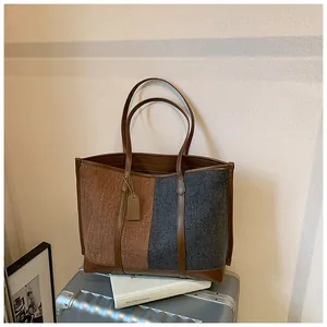 Detail der Kontrast-Tote-Bag mit Tweed-Struktur und braunen Ledergriffen am Henkel
