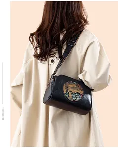 Close-up of vintage black leather pillow bag featuring ethnic strap and elephant pattern