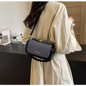 Détail du sac bandoulière en toile grise avec bordures en cuir noir et fermoir doré