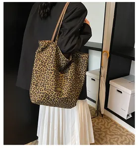 Detail of leopard print tote bag with brown slim handles shown on female model's shoulder