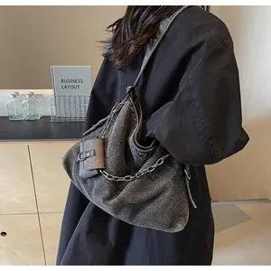 Close-up of grey denim tote bag with silver chain detail and small hanging pouch