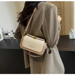 Détail du sac bandoulière bicolore avec tissu tissé, finitions cuir et fermoir doré