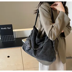 Detail of dark denim hobo tote with chunky metal chain and detachable mini pouch
