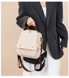 Detail view of the vintage geometric pattern and golden rivets on a creamy white backpack
