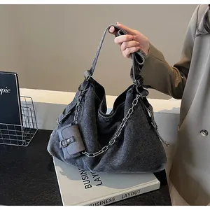 Detail of dark gray denim hobo bag with silver chain and matching mini pouch accessory