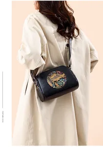 Detail of vintage black pillow bag with embossed elephant pattern and woven wide strap