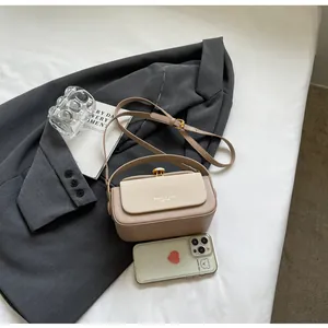 Détail d'un sac bandoulière beige et rose avec texture tressée sur un blazer gris