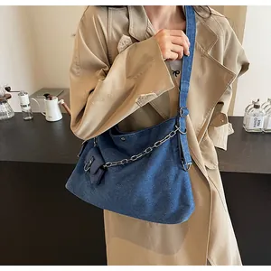 Blue denim hobo bag featuring silver chain detail and small coin pouch on a model