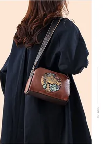 Detail view of vintage brown crossbody bag featuring artistic elephant embroidery and strap