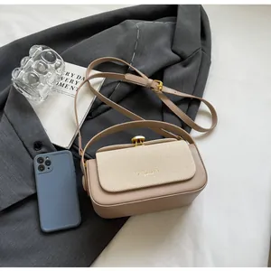 Détail du sac à main beige contrasté avec fermoir doré sur fond de blazer gris