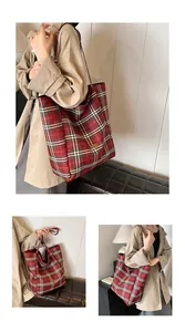 Close-up of red tartan tote bag featuring a vintage gold logo plate and shoulder straps