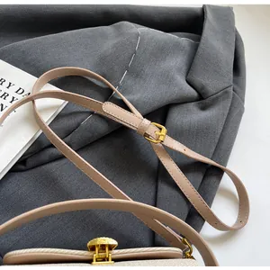 Détail du sac à bandoulière beige avec fermoir doré et cuir texturé élégant