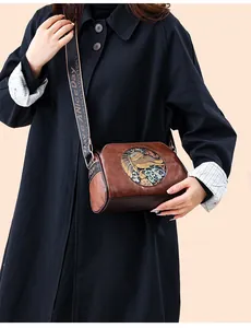Detail of vintage brown leather bag with elephant embossment and jacquard strap
