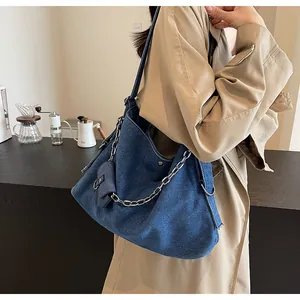 Detail of dark blue denim hobo bag featuring a silver chain and small detachable pouch