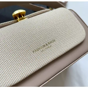 Détail du sac à main en tissu beige avec fermoir coquille doré et cuir lisse