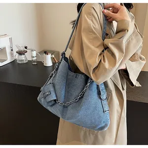 Detail of denim tote bag with silver chain and mini coin purse worn over the shoulder