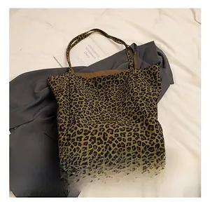 Detail view of large leopard print canvas tote bag laid on dark suit and white sheets