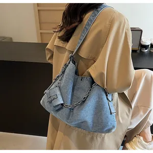 Detail of blue denim tote bag with silver chain strap and matching mini pouch accessory