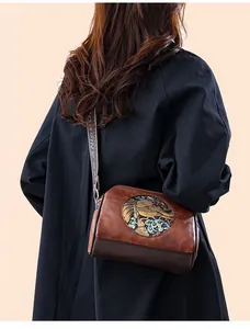 Detail of vintage brown crossbody bag with ethnic floral embossing and wide shoulder strap