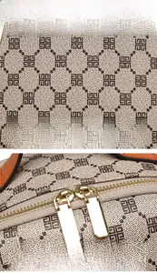 Close-up of golden dual metal zippers and geometric monogram pattern on the backpack