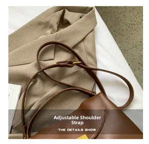 Detail view of adjustable shoulder strap on brown leather bag with gold hardware