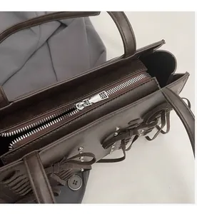 Detail of silver smooth zipper and tassel on dark brown suede bow shoulder bag