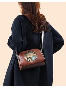 Detail of vintage brown crossbody bag featuring embossed elephant pattern on smooth leather