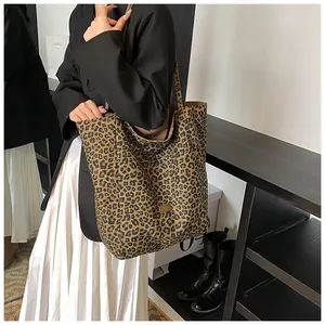 Close-up of leopard print tote bag with gold metal logo on soft canvas fabric