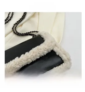 Detailed close-up of black leather bag with white faux shearling trim and metal chain