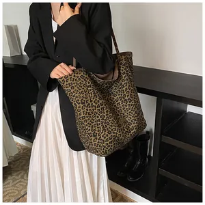 Detailed view of a leopard print tote bag with oval metal buckle and long shoulder straps