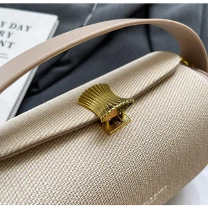 Gros plan d'un sac à main beige en tissu texturé avec un fermoir doré rétro en métal
