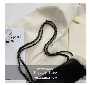 Detail of stitched chain strap on black leather shoulder bag with white faux fur trim